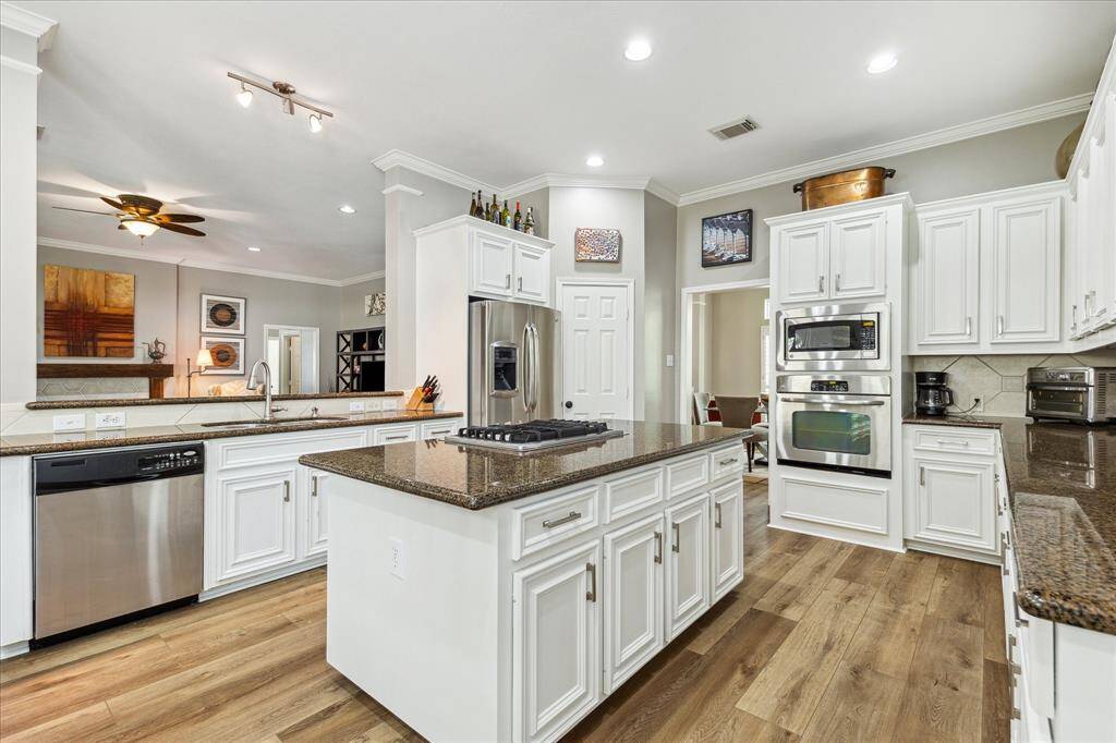 The kitchen features a gas downdraft cooktop, stainless appliances, and so much work space! You have room to store all your gadgets and goodies. The pantry is between the fridge (it can stay) and the formal dining room.