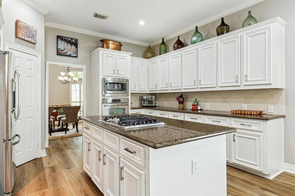 The island has power and a gas downdraft cooktop. It has granite counters and white cabinets with updated hardware.