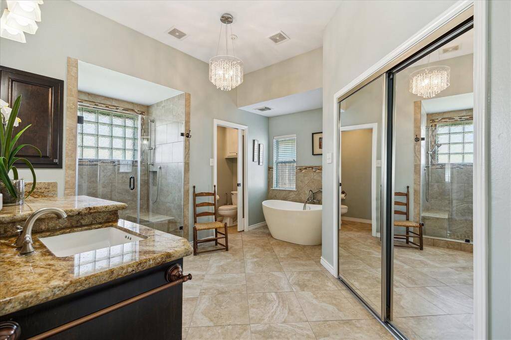 Here's your primary bath! There's a  soaking tub and a separate shower. The lavatory has a pocket door and there is a wall of cabinetry for all your toiletries and space for that Costco pack of TP!