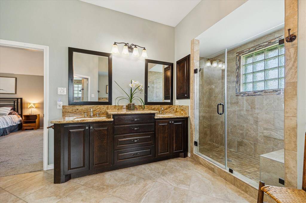 You can see the massive shower with a bench and a seamless enclosure beside your dual vanity.