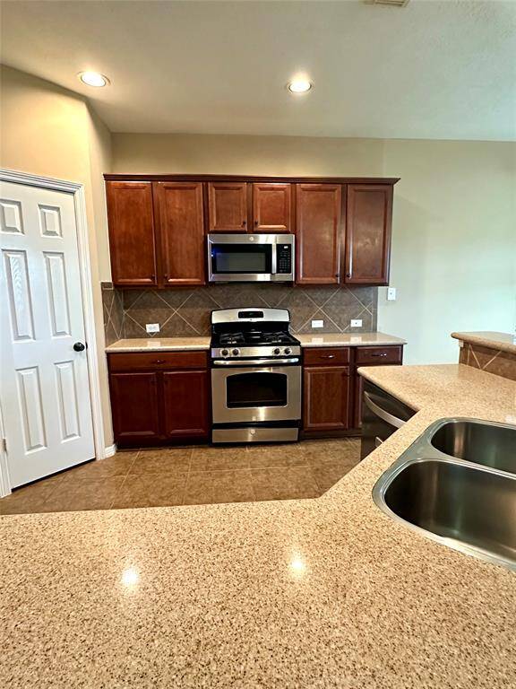 Recessed lighting in the kitchen provides additional brightness and aerial height.