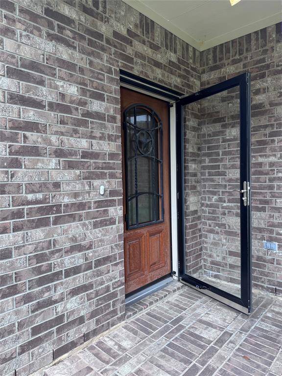 Wide Front Porch area with glass storm door in front of solid wood/iron door