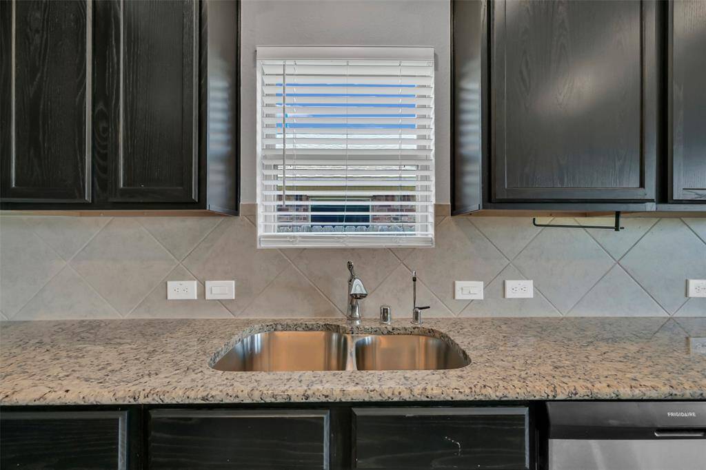 Notice the undermount sink with water dispenser. The tiled backsplash perfectly complements the light granite surfaces and darker cabinets.