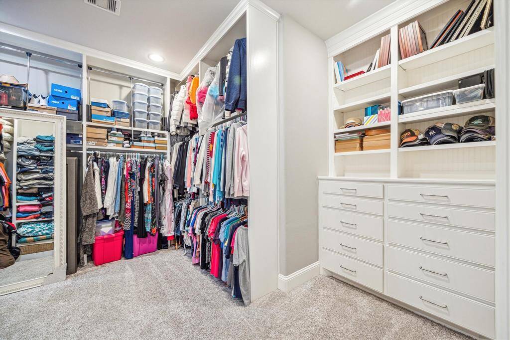Huge walk in closet with high ceilings and built in dressers.