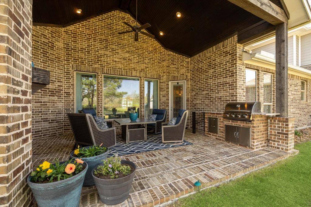 The outdoor kitchen space includes a gas grill, along with a vaulted tongue and groove wood ceiling with wood beams.