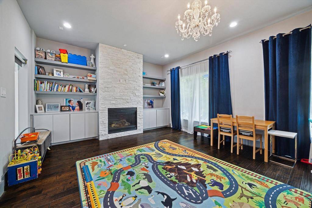 Stunning formal dining room area (currently used as a playroom) features custom built-ins with ample storage, electric fireplace, beautiful chandelier and dry bar (not pictured).