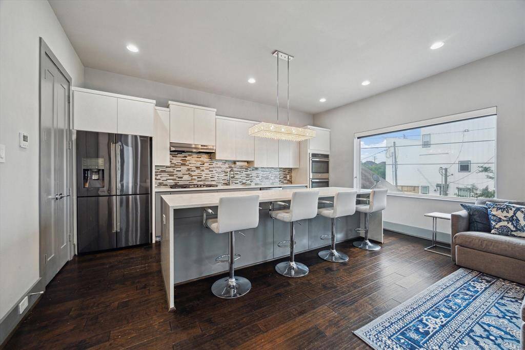 Beautiful gourmet kitchen includes large waterfall island w/ breakfast bar, SS appliances, gas cooktop and a custom pantry.