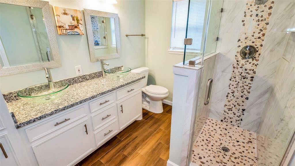 Master Suite Bathroom with Granite Counter Vanities, Framed Mirrors, Surround Tile and Pebbles Stand in shower.