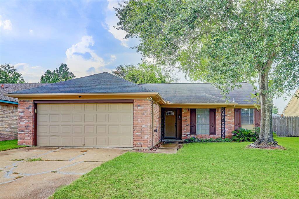 This charming brick home features a two-car garage, a well-maintained front lawn, and mature trees. The cozy front porch and large windows add to its welcoming appeal.