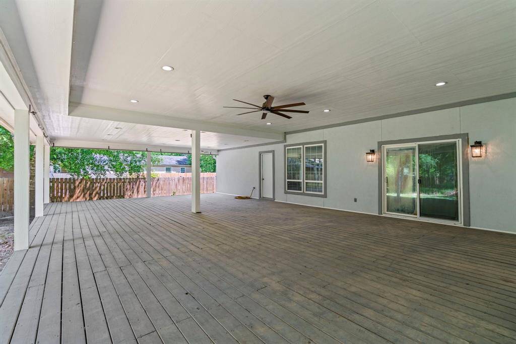 Spacious covered patio with a ceiling fan, recessed lighting, and sliding glass doors leading indoors. Ideal for outdoor entertainment and relaxation.