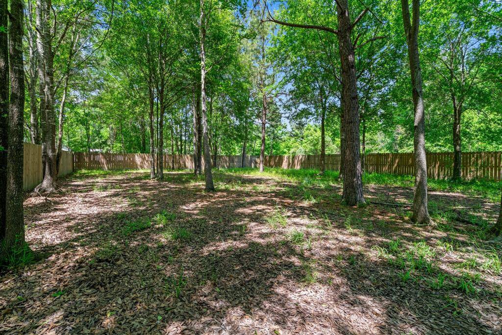 This photo showcases a spacious, wooded backyard with mature trees and a wooden fence, offering privacy and a natural setting perfect for outdoor activities.