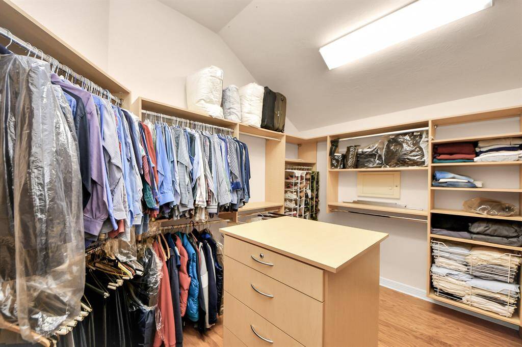 Primary closet with custom cabinetry and an in wall Safe.