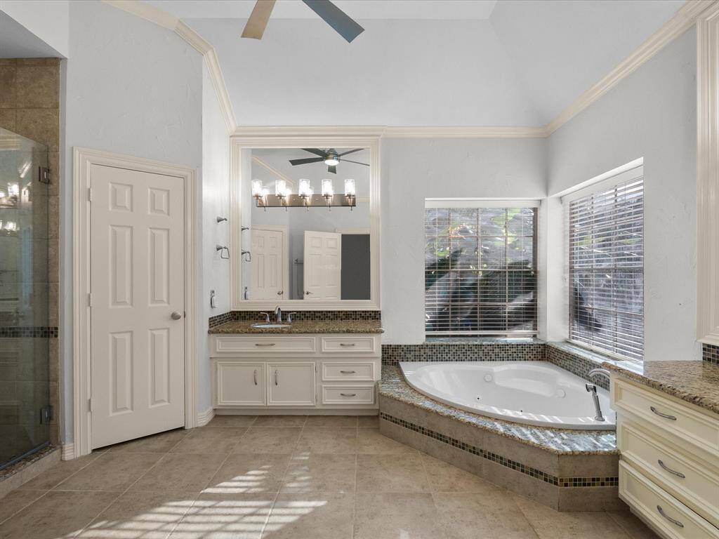 The primary bath has two vanities with sinks, a large jetted tub, and a separate shower.