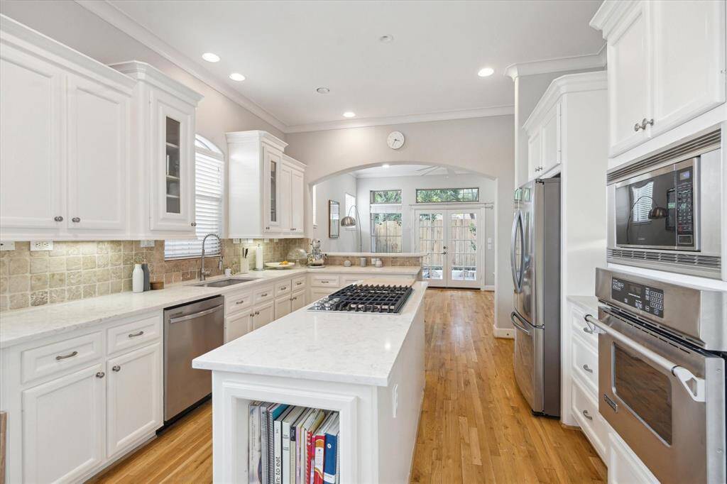 This island kitchen is meticulous in detail with high ceilings, tile backsplash, and hardwood floors that compliment the timeless color palette