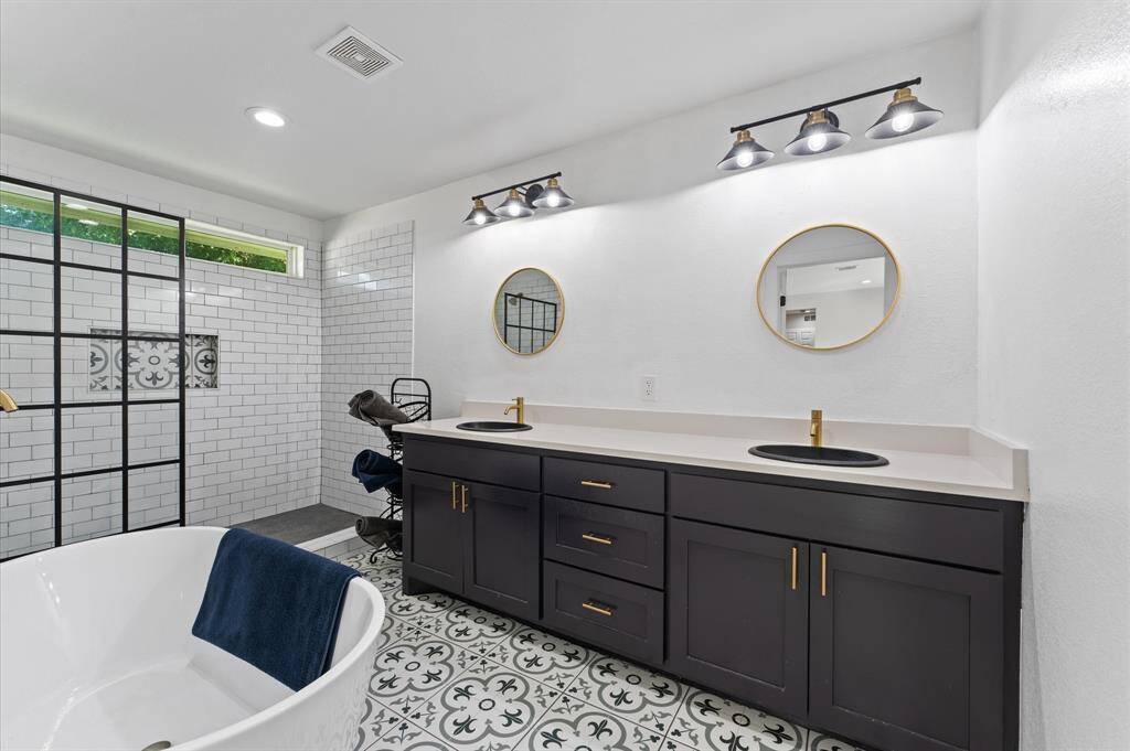 Luxurious primary bath with dual sinks, soaking tub, separate shower, and gold fixtures.