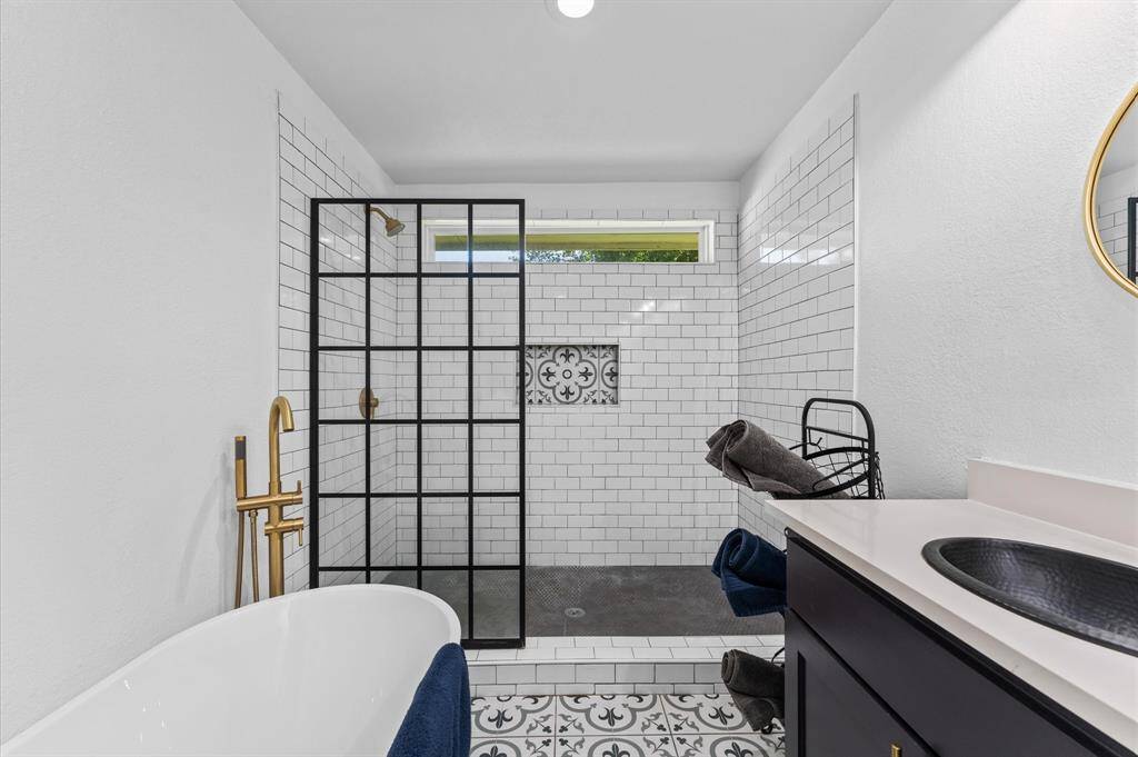 Luxurious primary bath with dual sinks, soaking tub, separate shower, and gold fixtures.