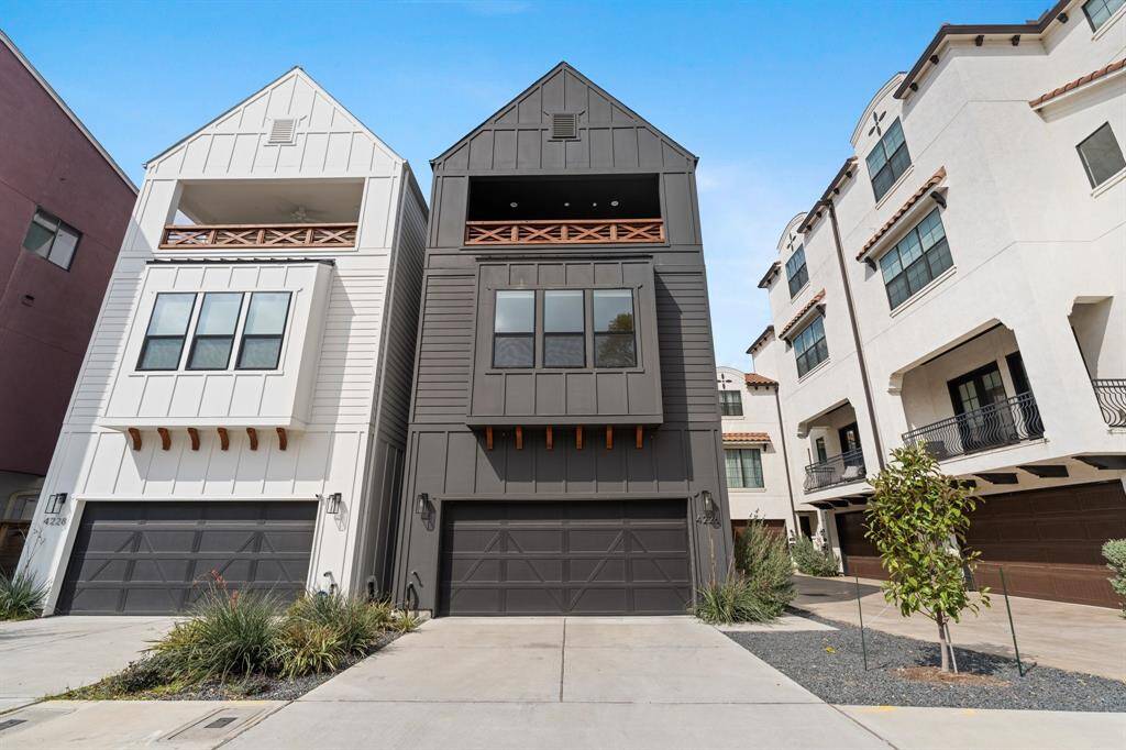 Modern townhomes with a sleek design, featuring three stories and large windows. Home includes a spacious 2-car garage and a driveway. The exterior is a mix of bold colors, with balcony railings adding charm.