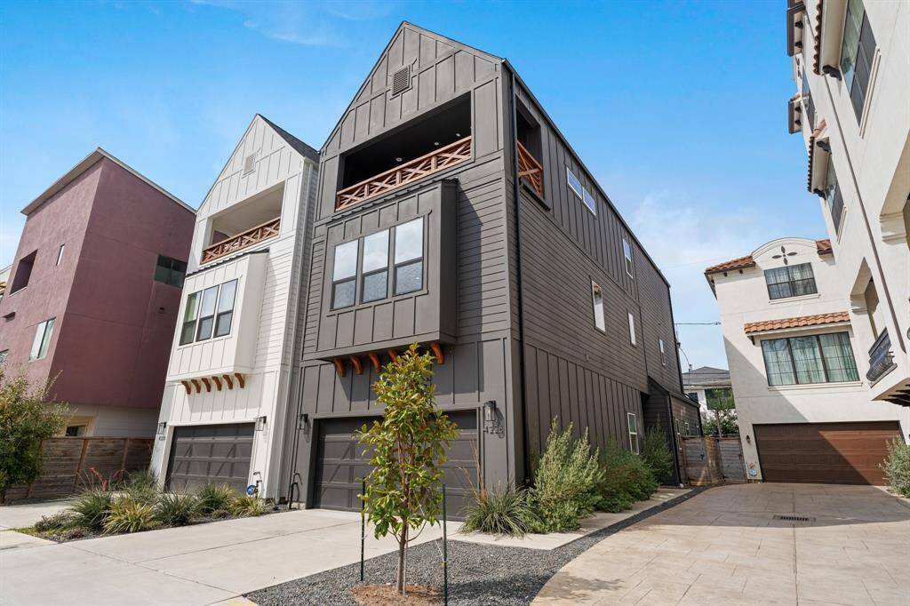 This modern townhouse features a sleek design with vertical siding and large windows, offering plenty of natural light. It includes a spacious garage and a small landscaped front area, set in a well-maintained neighborhood.