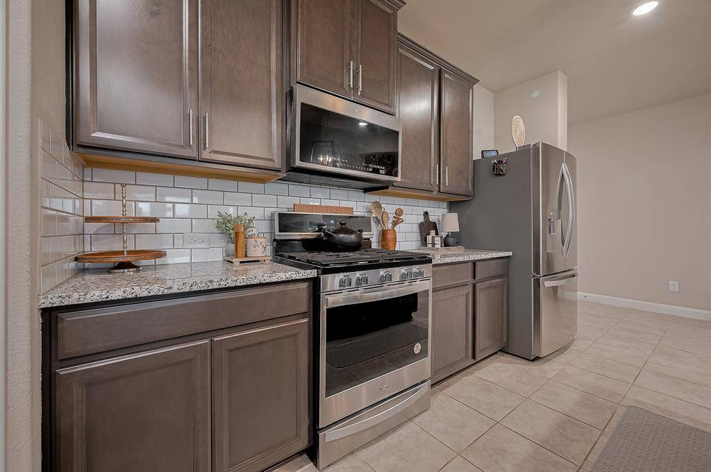 Features a subway tile backsplash and tile flooring, providing a sleek and functional cooking space.