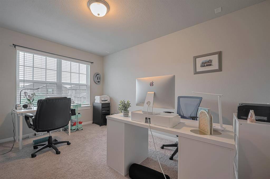 This photo showcases a bright home office. The room is carpeted, providing a cozy atmosphere, and features a neutral color scheme, making it versatile for any decor style.