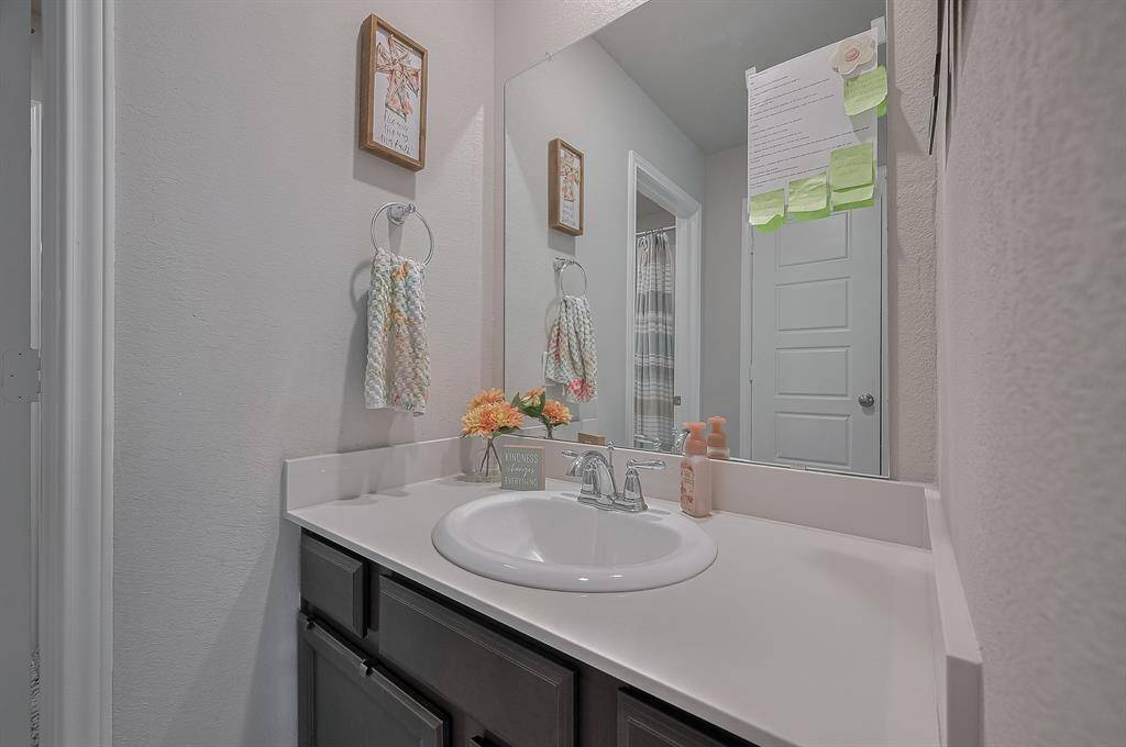 This bathroom features a clean, modern design with a single sink vanity, dark cabinetry, and a large mirror.