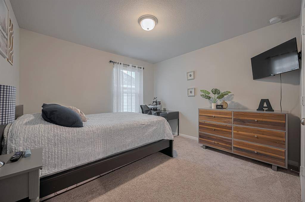 This bedroom features a cozy layout with neutral walls and carpet.
