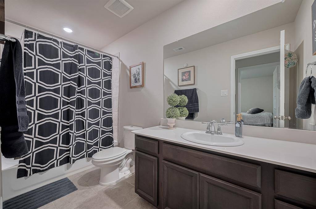 This bathroom features a modern design with a large mirror, dark wood vanity, and a sleek countertop.