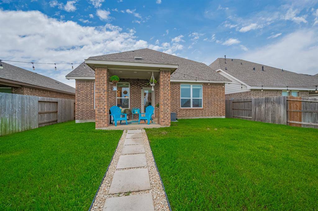 The backyard is spacious and well-maintained, enclosed by a wooden fence, and has a stone pathway leading to the patio, perfect for outdoor relaxation.