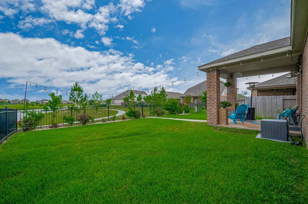 The area is fenced and offers a view of a scenic walking path and lake, providing a serene and inviting outdoor space.