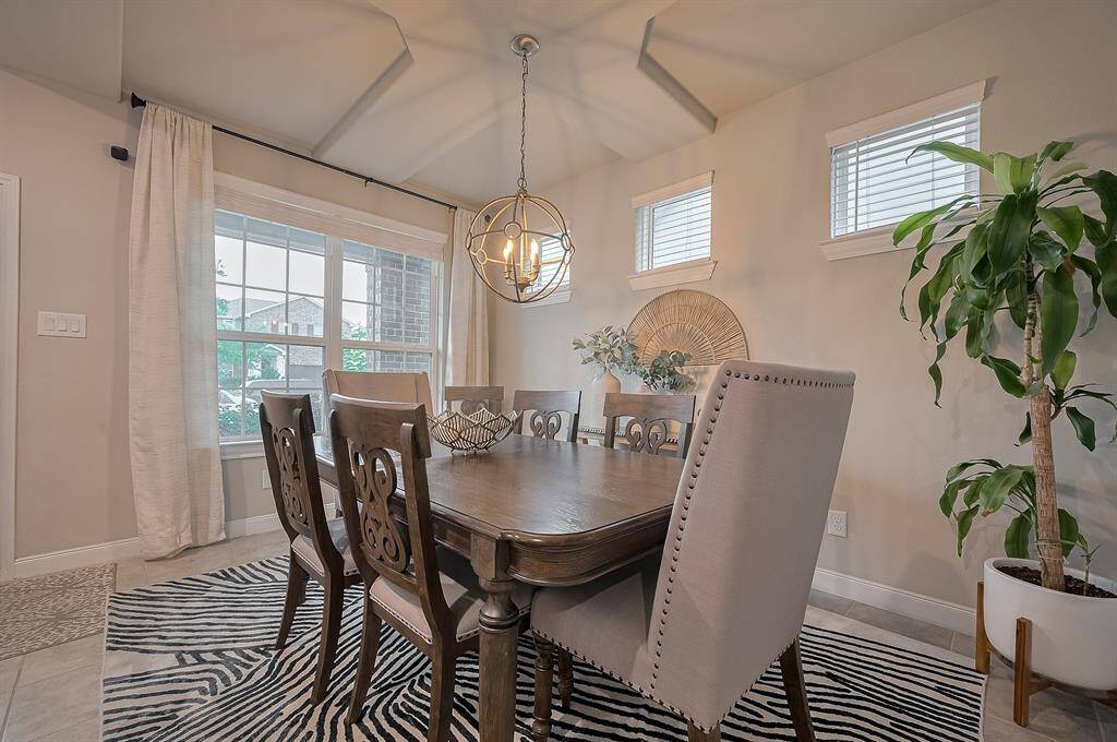 This dining area features a modern light fixture, and abundant natural light from large windows.