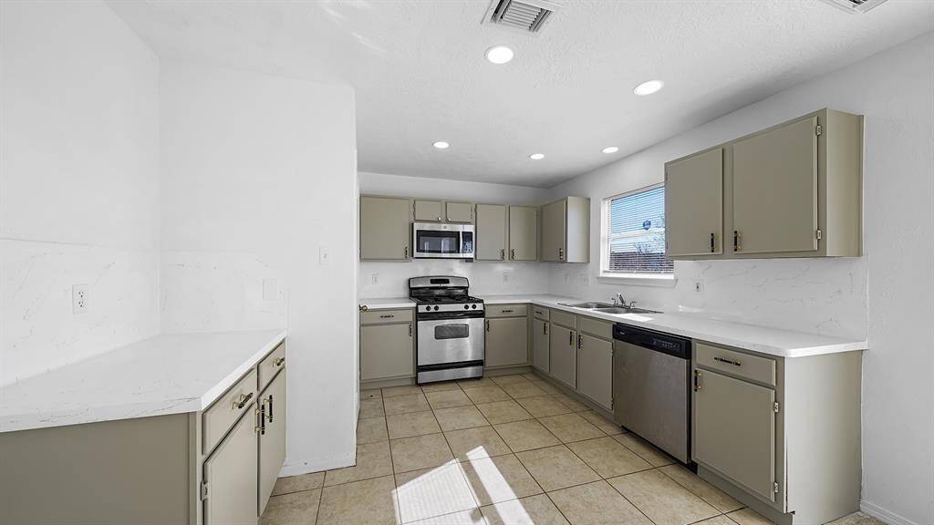 Alternative view of the kitchen showcasing the modern cabinets complemented by the white countertops.