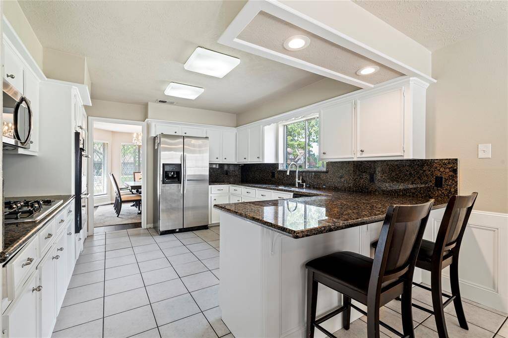 Spacious kitchen with granite countertops, bar seating, and plenty of cabinet storage—ideal for everyday cooking and casual dining.