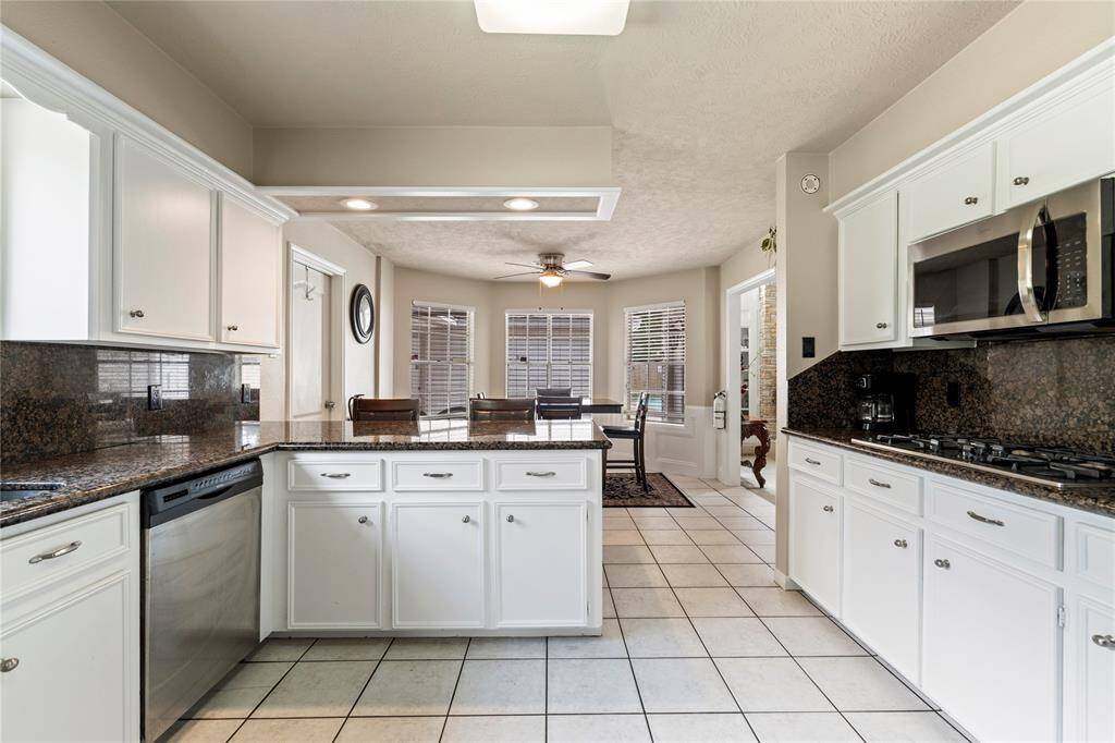 Open and well-organized, this kitchen features a center island, granite countertops, and a seamless connection to the dining and living areas