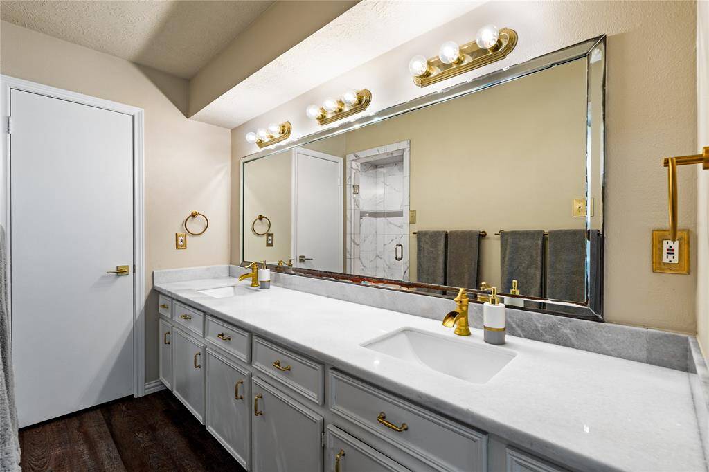 The primary bath offers dual sinks, plenty of cabinet space, and a walk-in shower with a timeless tile surround.