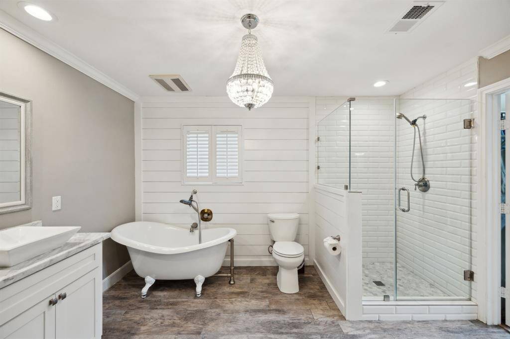 Luxurious bath boasts shiplap accent wall, soaking tub, double sinks, and a walk-in closet.