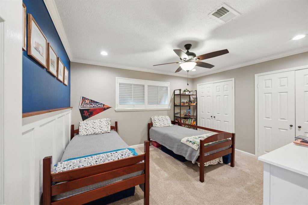 Another guest bedroom with wainscoting accent wall, two closets, and ceiling fan.