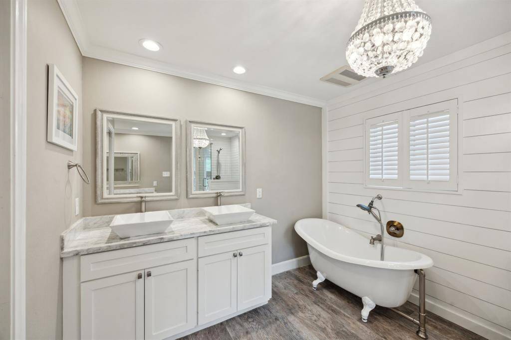 This view of the primary bath shows the double vessel sinks, beautiful chandelier, and a close up of the shiplap accent wall.