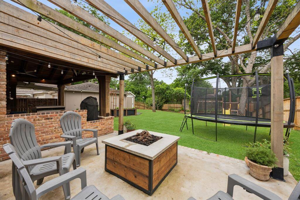 Separate pergola with fire pit enhanced by string lights.