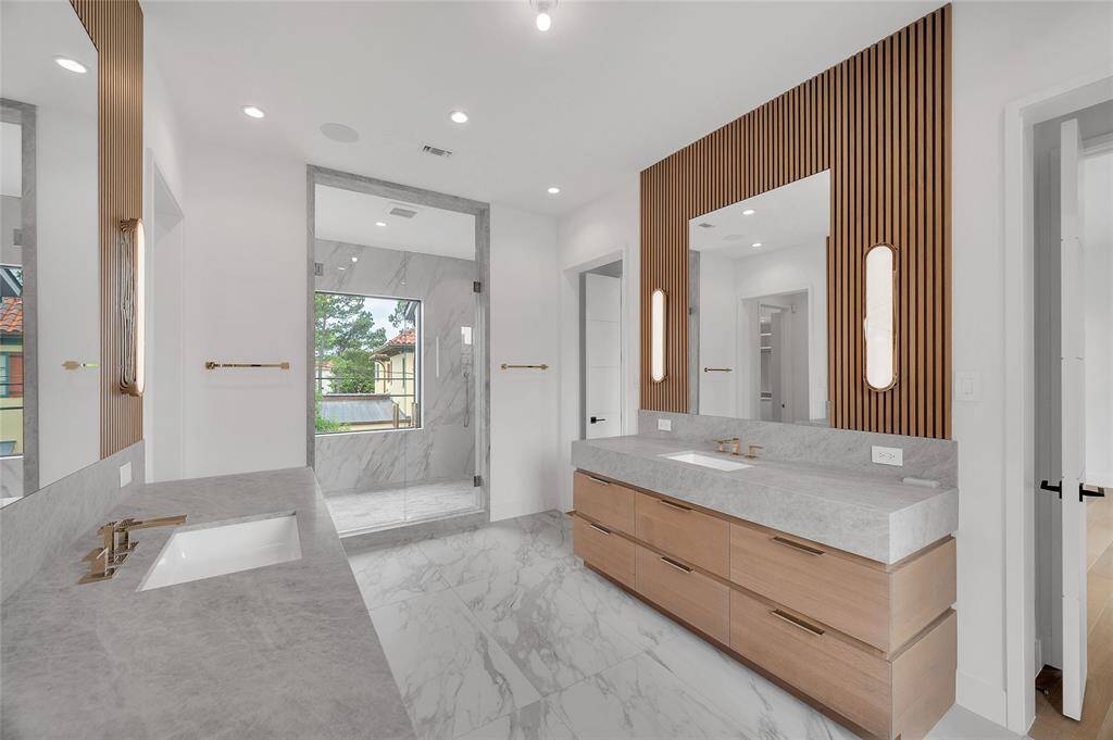 [Primary Bath]The lavishly-appointed primary bath features quartzite surfaces; Circa lighting; acoustical paneling above the sink cabinets; a wet room with window, Bain Ultra soaking tub, and shower area with two wall and one hand-held showerheads; and a water closet with TOTO commode.