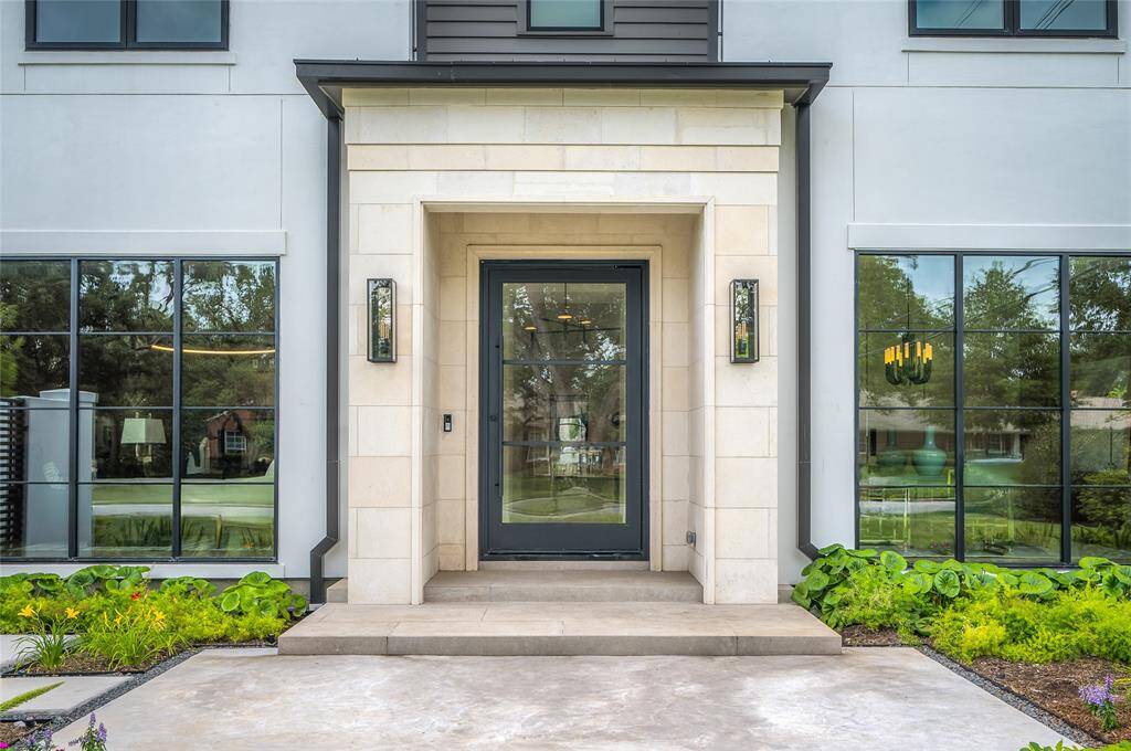 [Front Entrance]A towering glass and metal pivot door opens into the light-filled foyer.