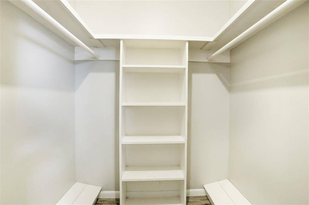 Primary closet which includes built-in shoe storage, shelving, and galley hanging bars.