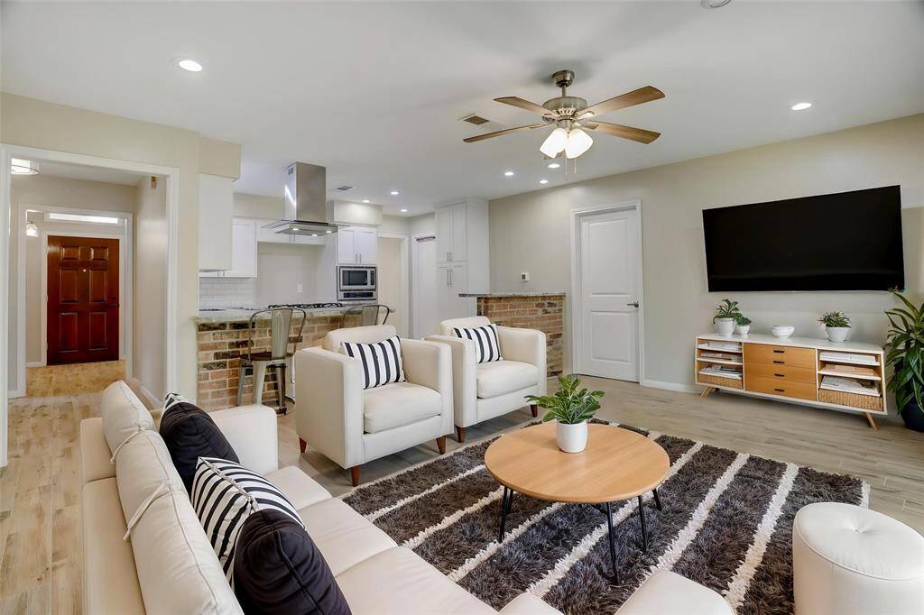 Another virtually staged angle of the living room, showcasing the openness to the kitchen and walkway to the front door.