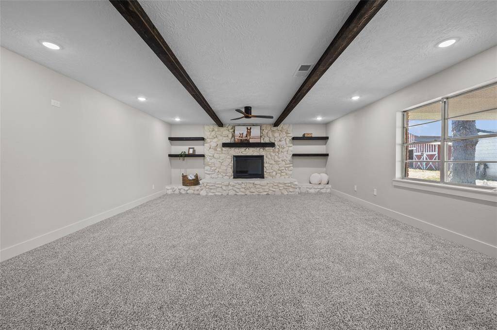 Huge, recently remodeled family room features new beams, paint and carpet.  The stone fireplace and floating shelves really compliment this space.