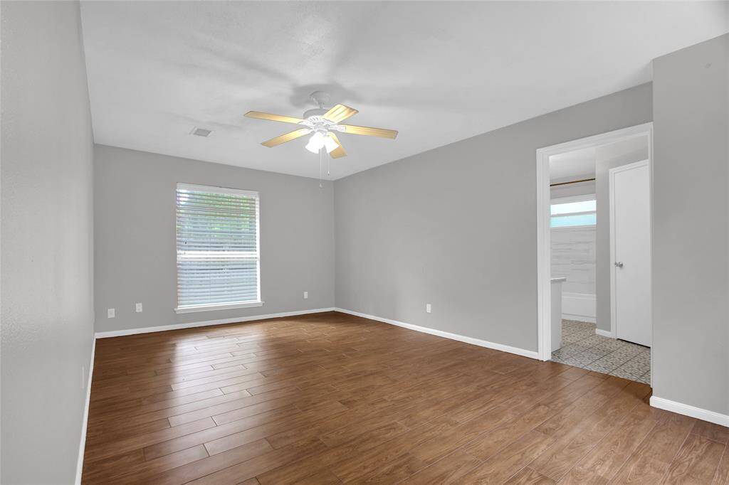 Spacious and serene primary suite featuring elegant hardwood look floors and abundant natural light.