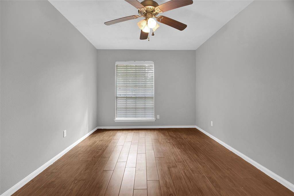 Inviting guest bedroom with elegant hardwood look tile floors and ample natural light.
