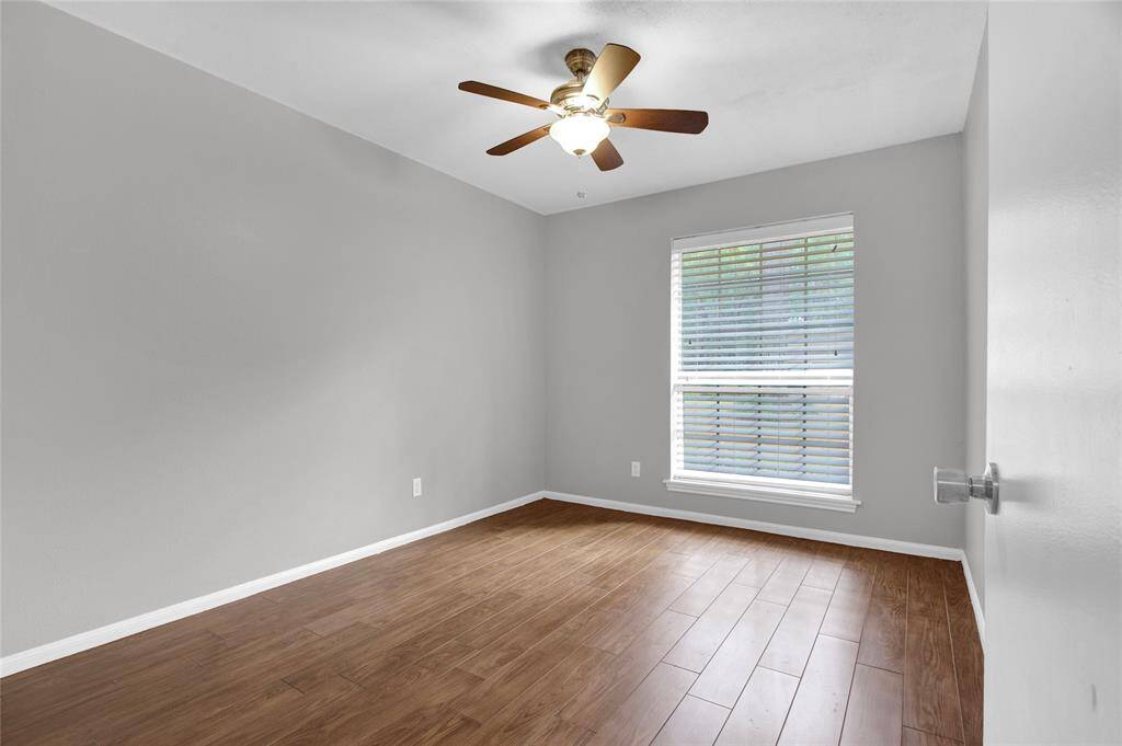 Charming Guest Bedroom: Bright, Cozy Space with Wood Look Flooring and Modern Ceiling Fan.