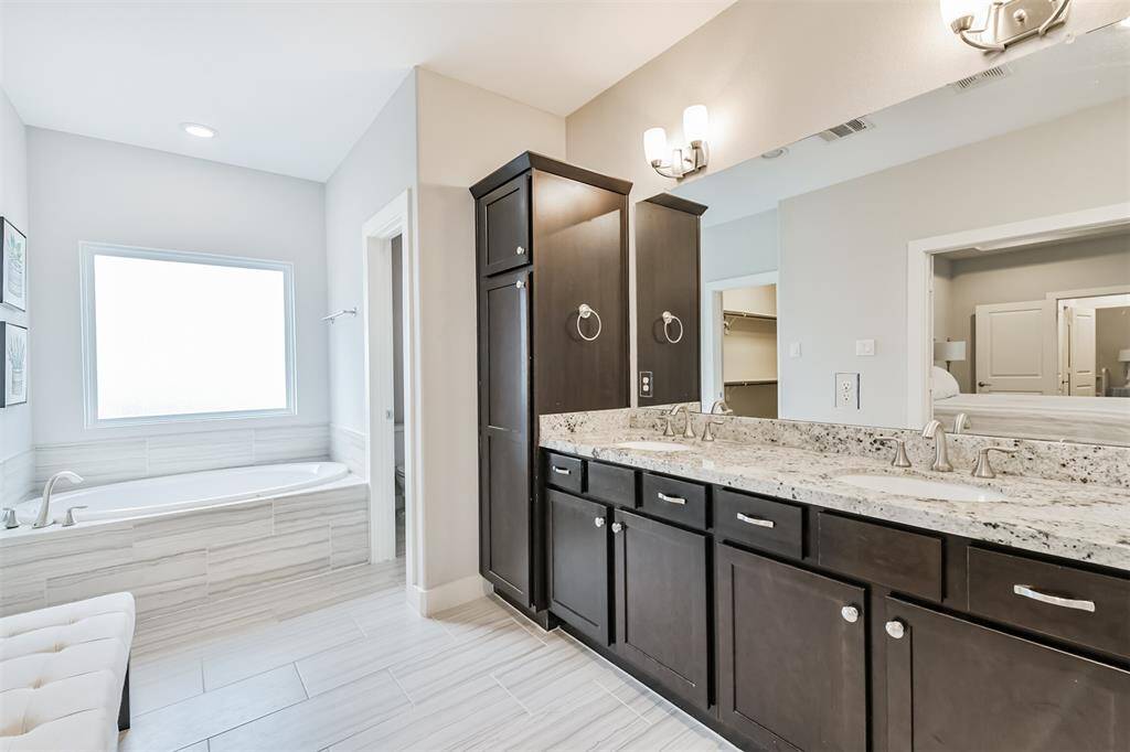 The primary bathroom features a soaking tub with a large frosted glass window, double sinks, separate water closet for the toilet, ample storage, and a grand walk in shower.