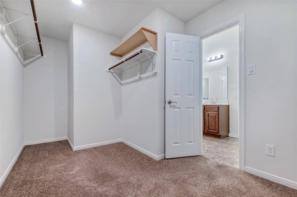 Huge primary closet suited for a Queen with nice carpet flooring and extra shelving.