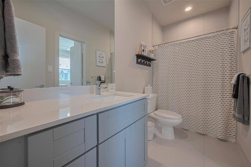 This well-appointed full bath features quartz countertops, sleek cabinetry, modern tile flooring, and a spacious tub-shower combo—perfect for guests or daily family use.