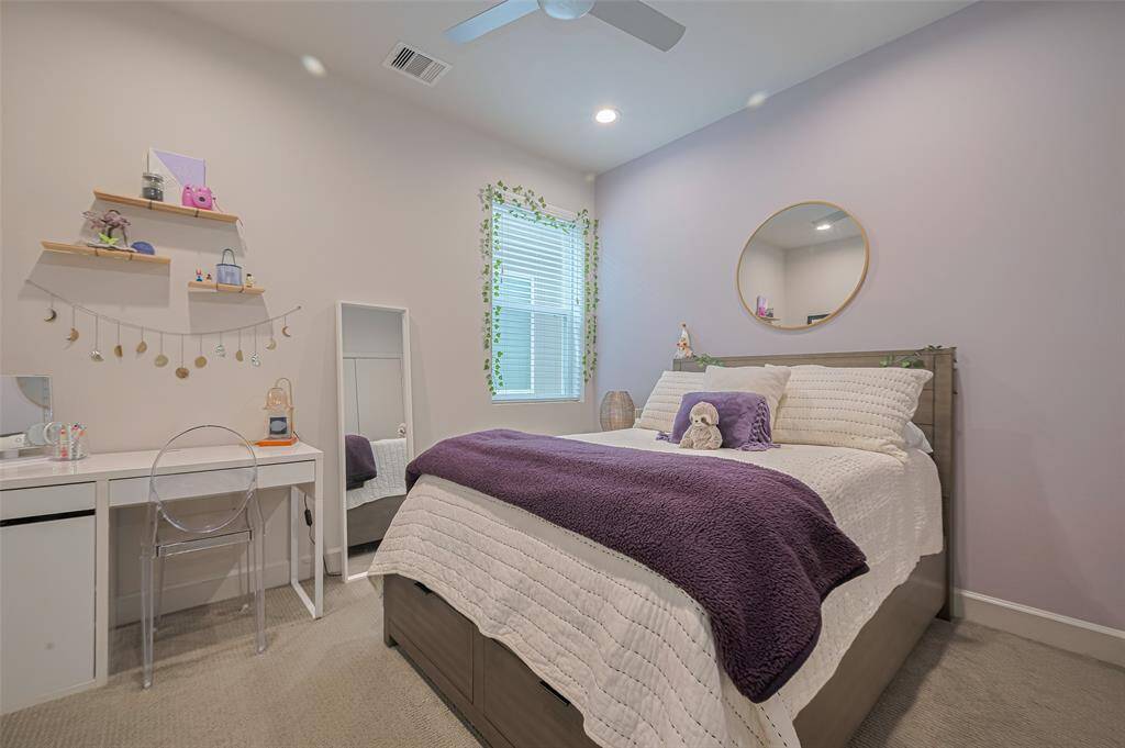 This peaceful bedroom retreat features a calming lavender accent wall, recessed lighting, double-door closet, and a cozy layout—perfect for rest, guests, or a stylish personal escape.